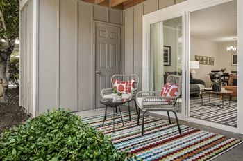 Covered patio with wicker chairs and colorful striped rug